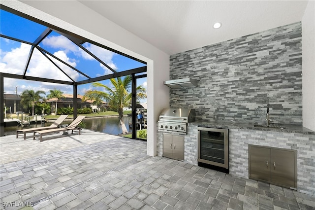 view of patio featuring a water view, area for grilling, sink, and wine cooler