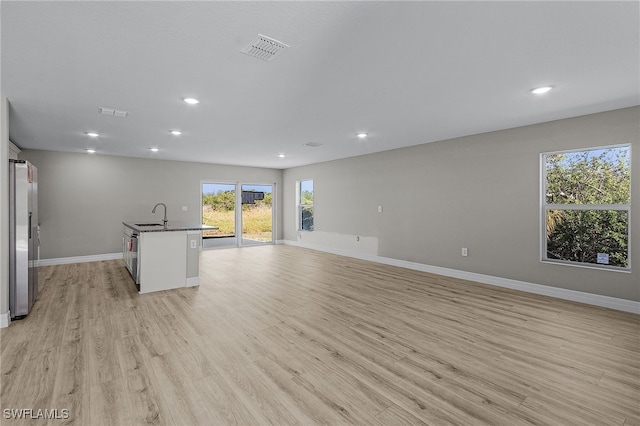 unfurnished living room featuring light hardwood / wood-style flooring and sink