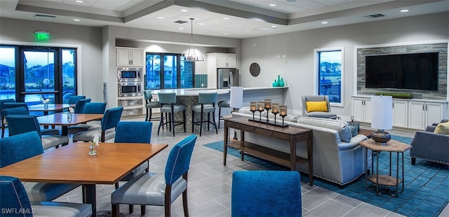 living room featuring a notable chandelier, a raised ceiling, and light tile patterned flooring