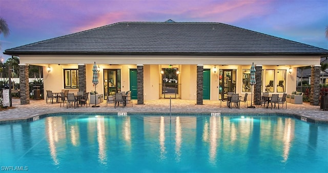 pool at dusk with a patio area