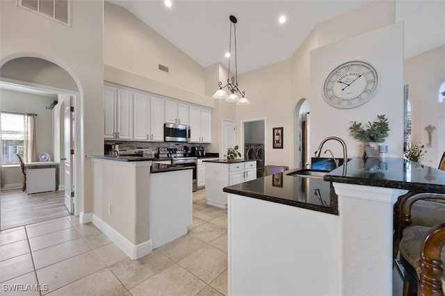 kitchen featuring sink, kitchen peninsula, pendant lighting, stainless steel appliances, and white cabinets