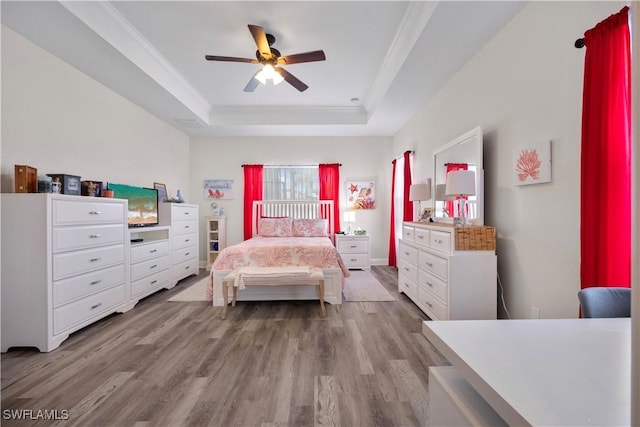 bedroom with a raised ceiling, ornamental molding, ceiling fan, and light hardwood / wood-style flooring