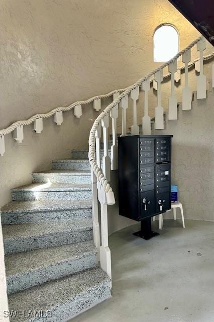 stairway featuring concrete floors and mail boxes