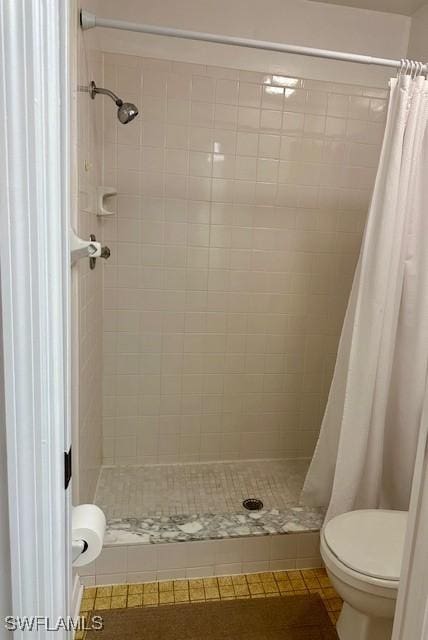 bathroom featuring tile patterned flooring, toilet, and walk in shower