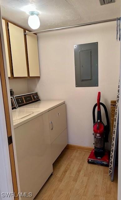 clothes washing area with cabinets, electric panel, light wood-type flooring, and washing machine and clothes dryer