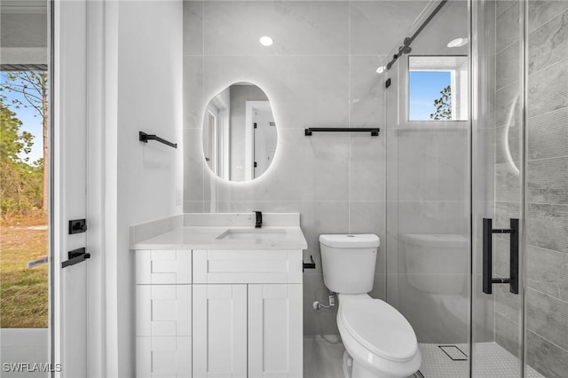 bathroom with toilet, vanity, tile walls, and an enclosed shower