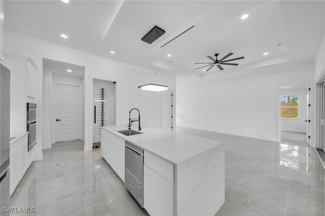 kitchen featuring a center island with sink, sink, a tray ceiling, appliances with stainless steel finishes, and white cabinets