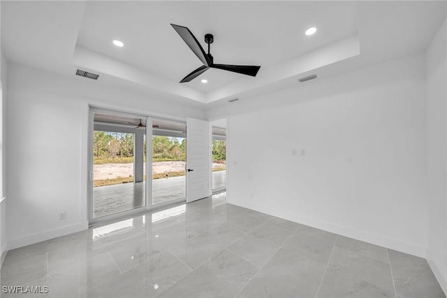 unfurnished room with ceiling fan and a tray ceiling