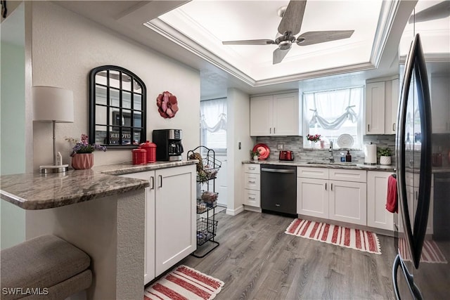 kitchen with black refrigerator, dishwashing machine, white cabinetry, and kitchen peninsula