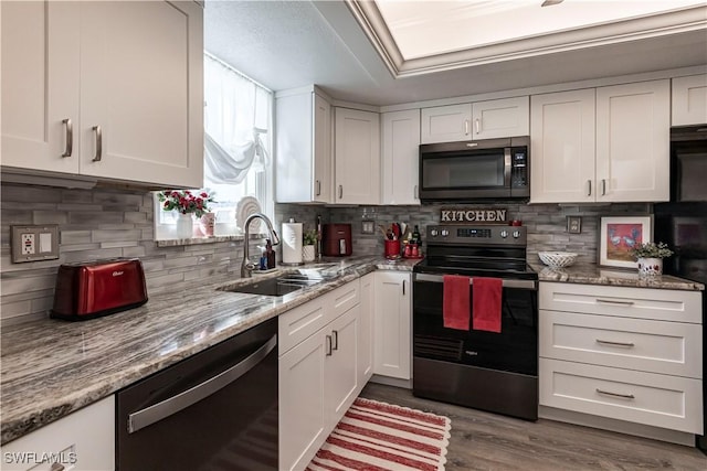 kitchen with sink, stainless steel range with electric stovetop, dishwasher, light stone countertops, and white cabinets