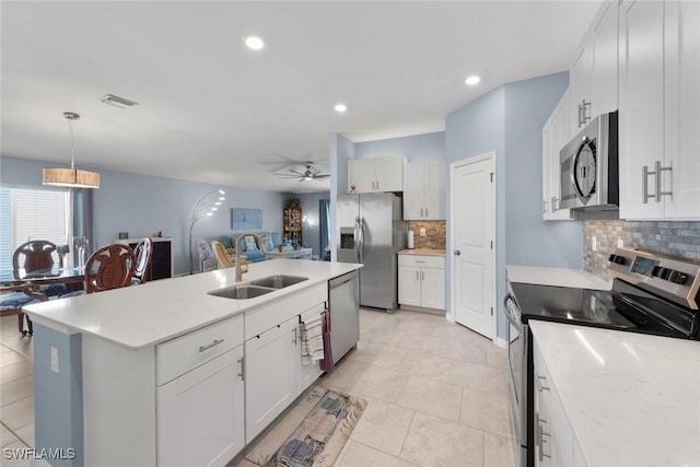 kitchen with appliances with stainless steel finishes, sink, a center island with sink, and white cabinets