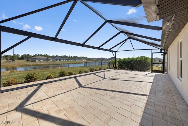 view of patio with a water view and glass enclosure