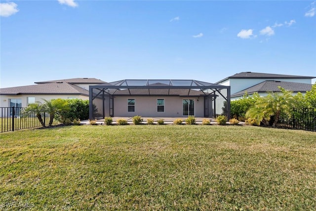 rear view of house featuring a yard and glass enclosure