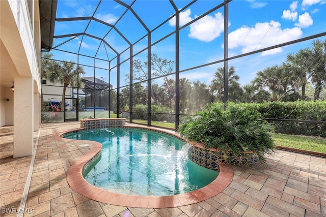 view of pool with a patio, pool water feature, and glass enclosure