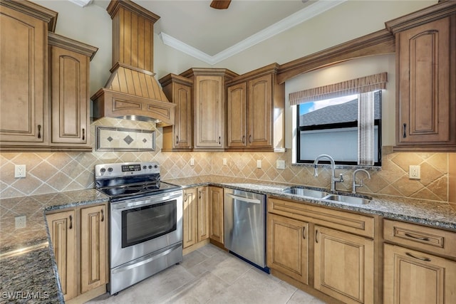 kitchen with premium range hood, sink, crown molding, dark stone countertops, and appliances with stainless steel finishes