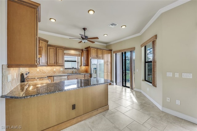 kitchen featuring sink, crown molding, appliances with stainless steel finishes, dark stone countertops, and backsplash