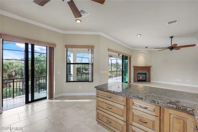 kitchen featuring ornamental molding, dark stone counters, ceiling fan, and light tile patterned flooring