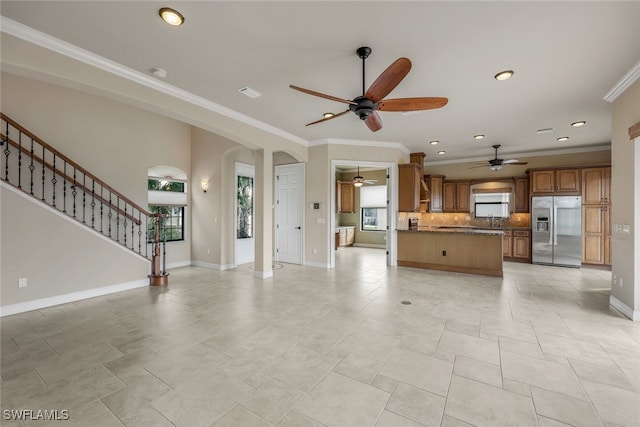 unfurnished living room featuring sink, ornamental molding, and ceiling fan