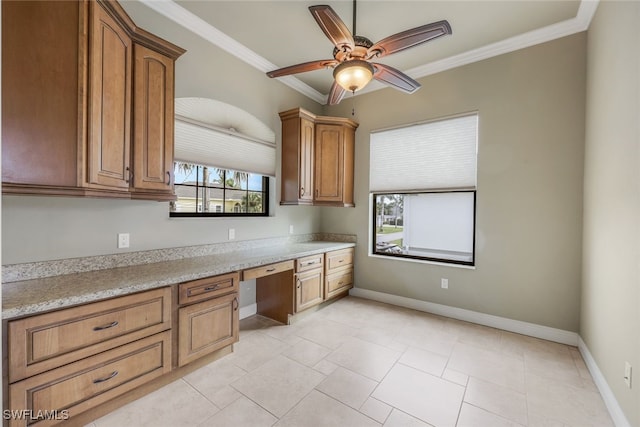 kitchen with crown molding, built in desk, light tile patterned floors, ceiling fan, and light stone countertops