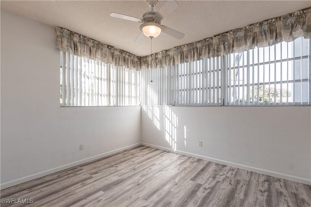 spare room with ceiling fan, plenty of natural light, a textured ceiling, and light wood-type flooring