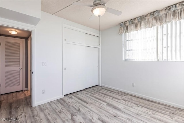 unfurnished bedroom with ceiling fan, a closet, a textured ceiling, and light wood-type flooring