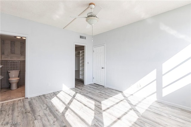 unfurnished bedroom featuring a textured ceiling, light wood-type flooring, and a closet