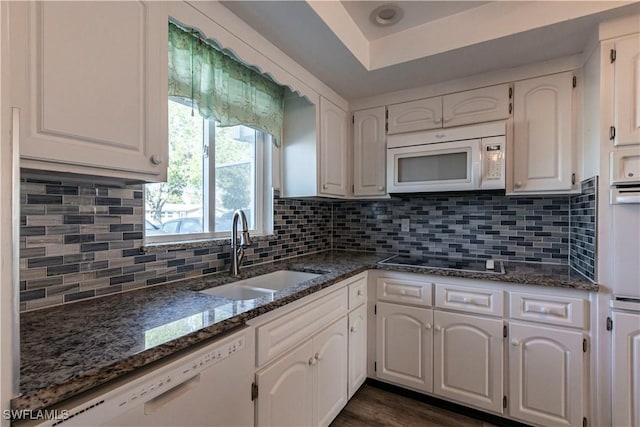 kitchen featuring sink, white appliances, white cabinetry, decorative backsplash, and dark stone counters