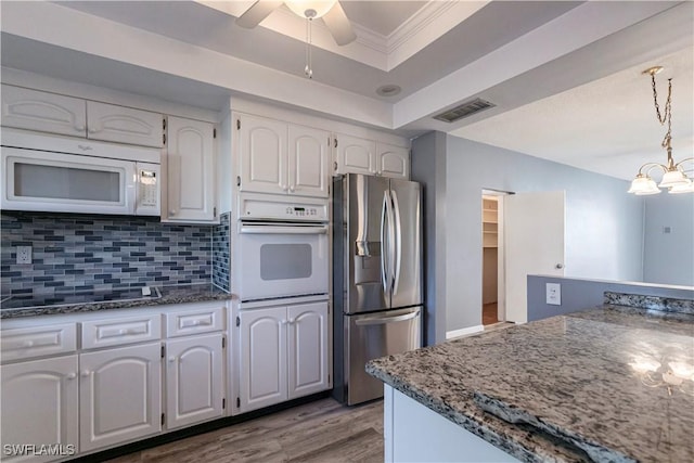 kitchen with pendant lighting, white appliances, a raised ceiling, and white cabinets