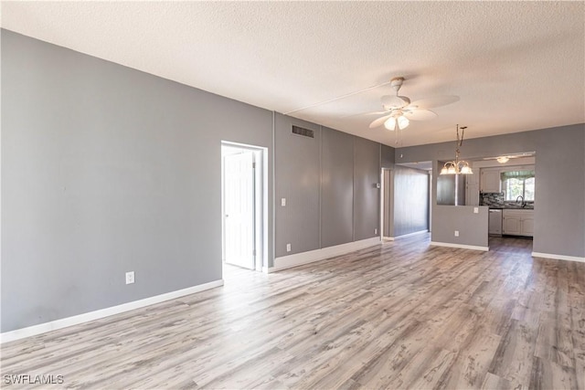 spare room featuring sink, ceiling fan with notable chandelier, a textured ceiling, and light hardwood / wood-style flooring