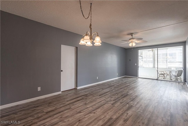 spare room featuring ceiling fan with notable chandelier, dark wood-type flooring, and a textured ceiling