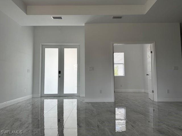 spare room with a tray ceiling and french doors