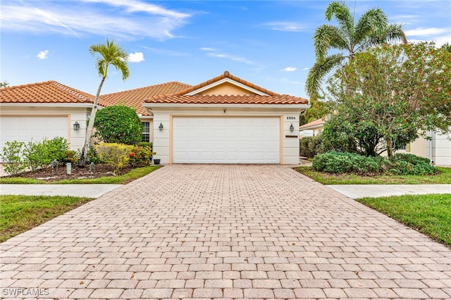 view of front facade featuring decorative driveway, a tiled roof, an attached garage, and stucco siding