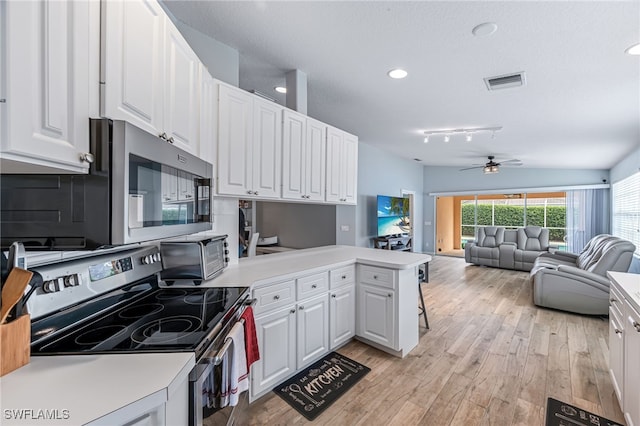 kitchen featuring white cabinets, stainless steel appliances, rail lighting, kitchen peninsula, and light hardwood / wood-style flooring