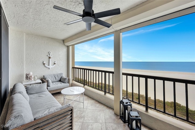 sunroom featuring a beach view, ceiling fan, and a water view