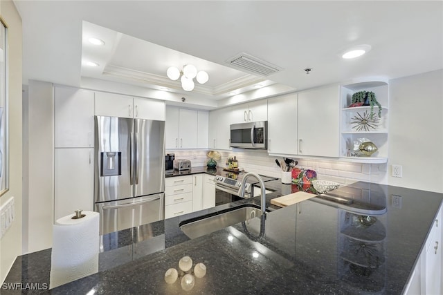 kitchen featuring stainless steel appliances, white cabinetry, a raised ceiling, backsplash, and dark stone counters