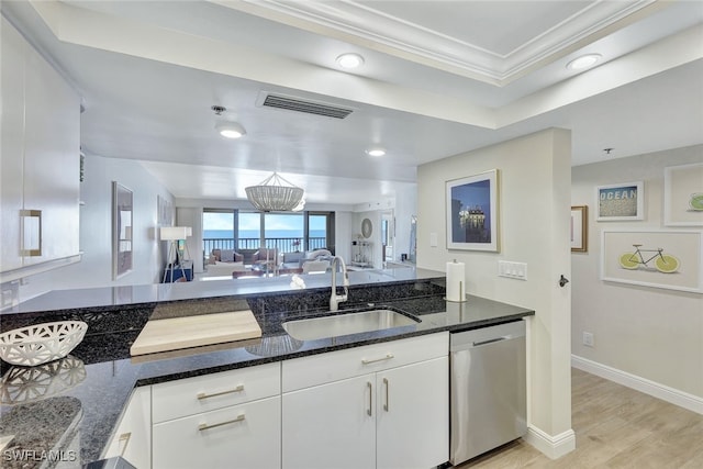 kitchen with white cabinets, dishwasher, dark stone countertops, sink, and a tray ceiling