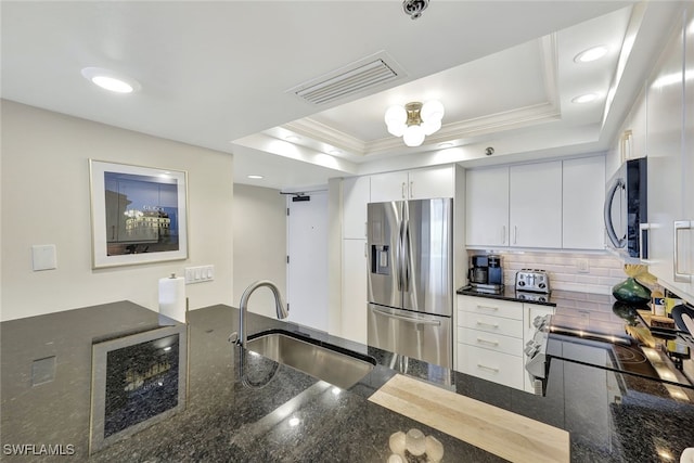 kitchen with sink, white cabinets, a raised ceiling, and stainless steel appliances