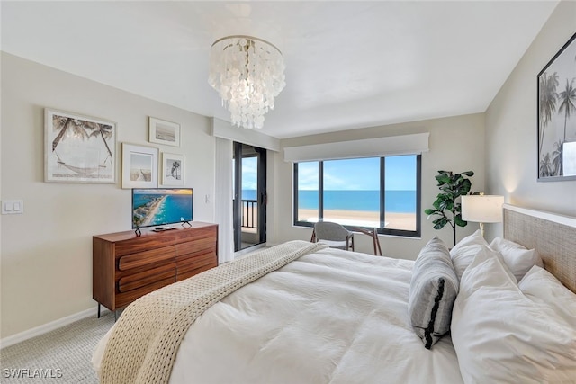 carpeted bedroom featuring access to exterior and a notable chandelier