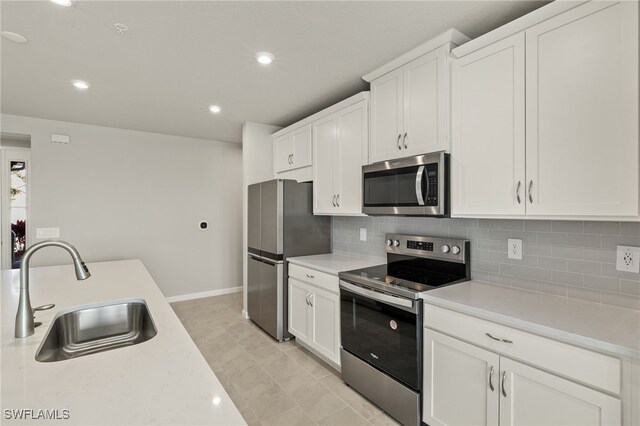 kitchen featuring a sink, decorative backsplash, appliances with stainless steel finishes, and light countertops