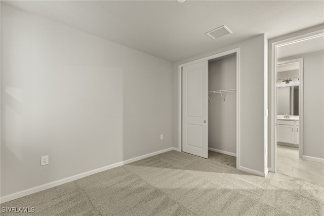 unfurnished bedroom with a closet, light colored carpet, baseboards, and a sink