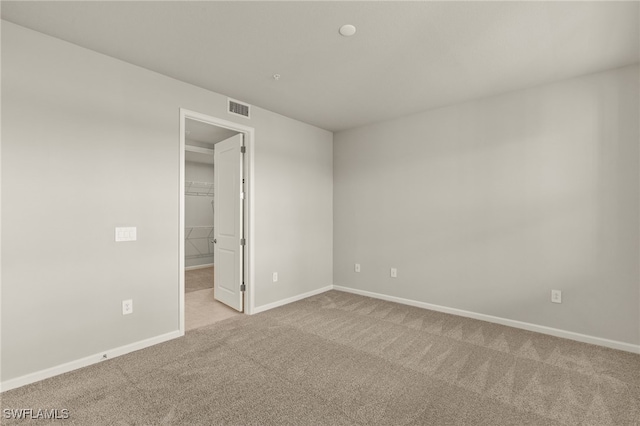 carpeted spare room with visible vents and baseboards