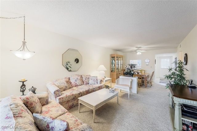 carpeted living room featuring ceiling fan and a textured ceiling