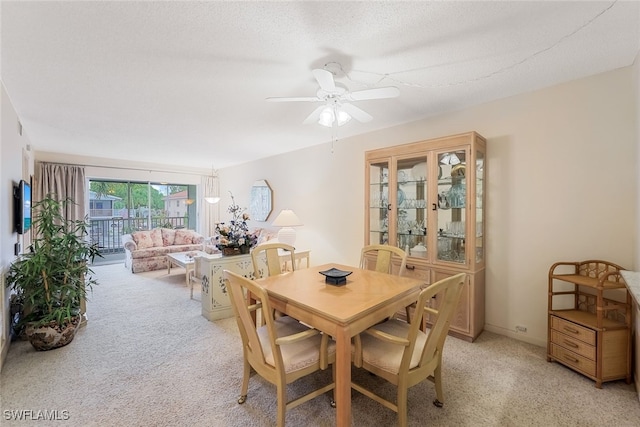 carpeted dining area with a textured ceiling and ceiling fan