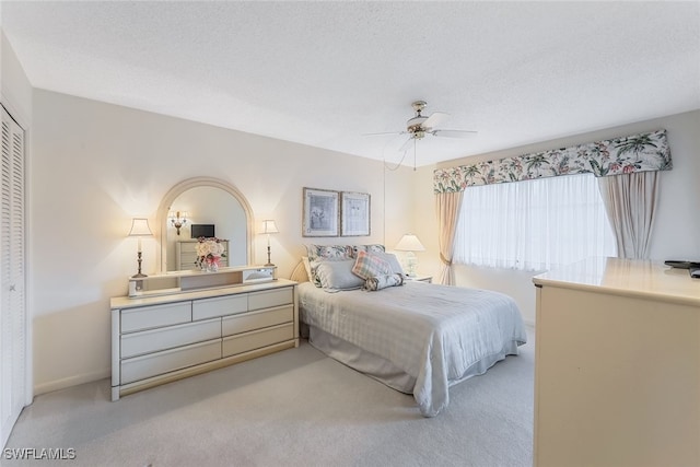 carpeted bedroom featuring a textured ceiling, ceiling fan, and a closet