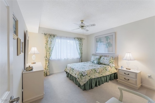 carpeted bedroom featuring ceiling fan and a textured ceiling