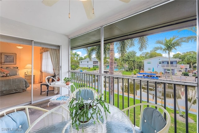 sunroom featuring ceiling fan and a water view