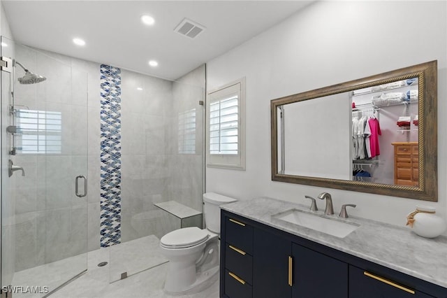 bathroom featuring vanity, a shower with shower door, and toilet