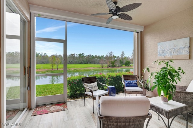 sunroom featuring ceiling fan and a water view