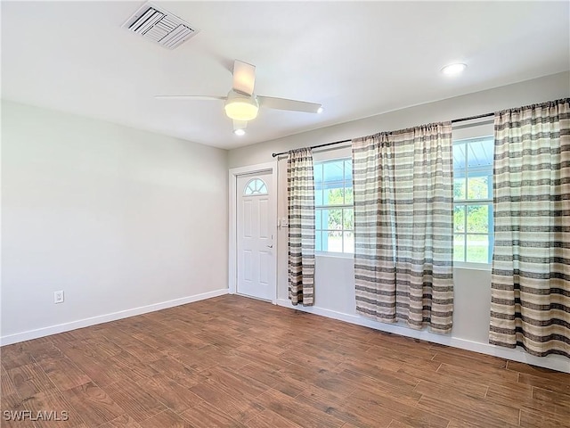 spare room featuring ceiling fan, wood-type flooring, and a healthy amount of sunlight