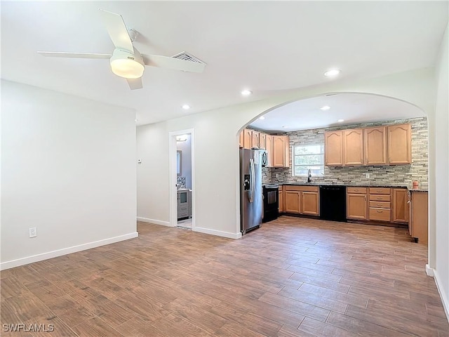 kitchen featuring ceiling fan, backsplash, black appliances, hardwood / wood-style flooring, and light stone counters